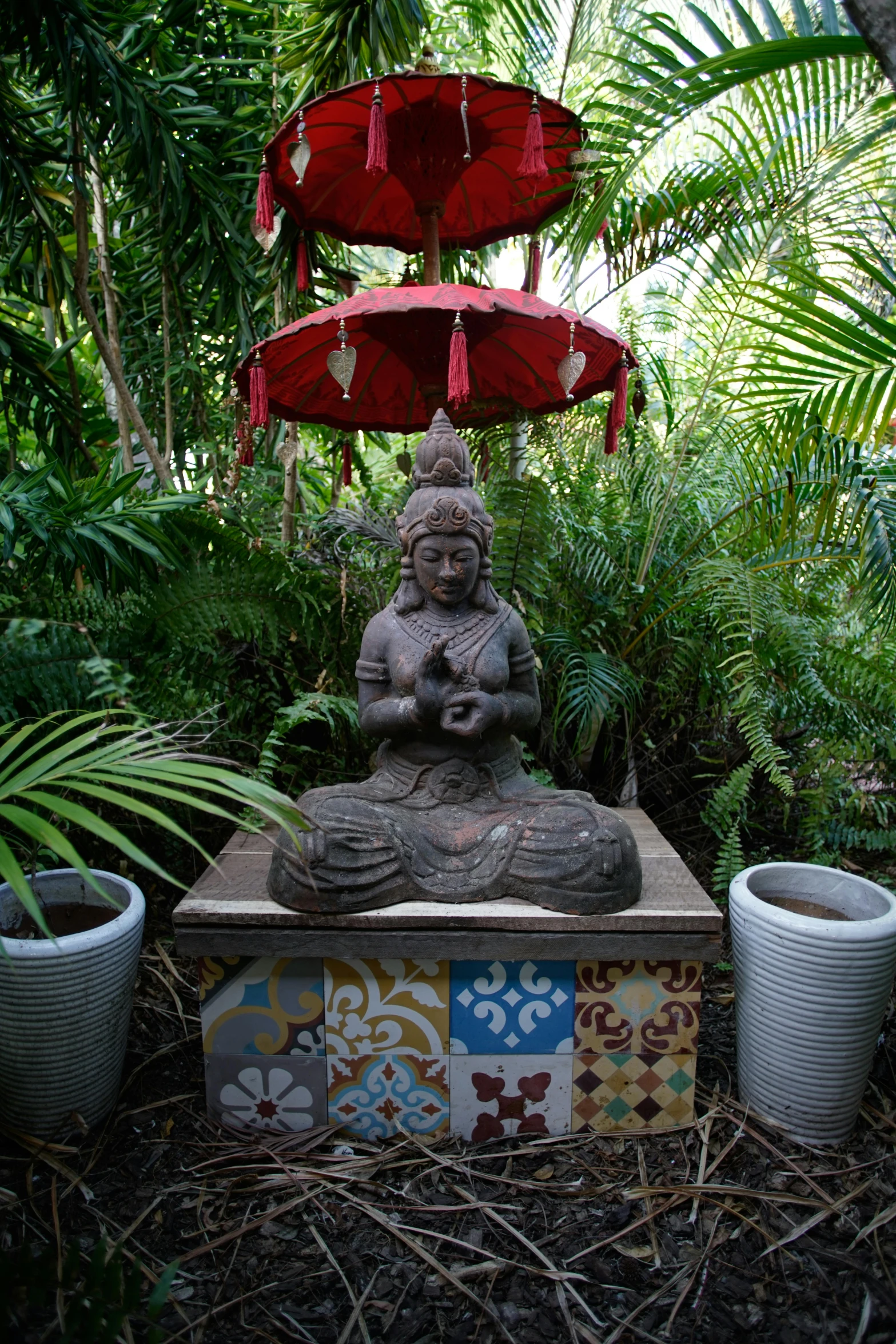 a sculpture sitting in a forest with three umbrellas