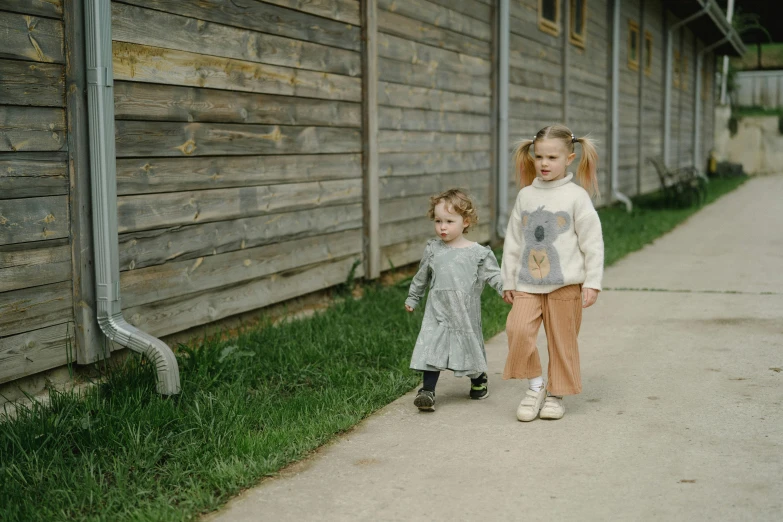 two little girls walking hand in hand outside a house