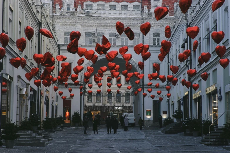 this image shows many people walking in front of some very decorative red hearts on the street