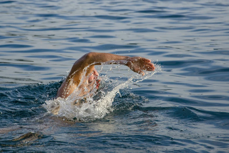 a man swims through the water in a swimming cap