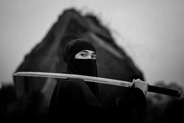 a woman with a long wooden stick in front of a mountain