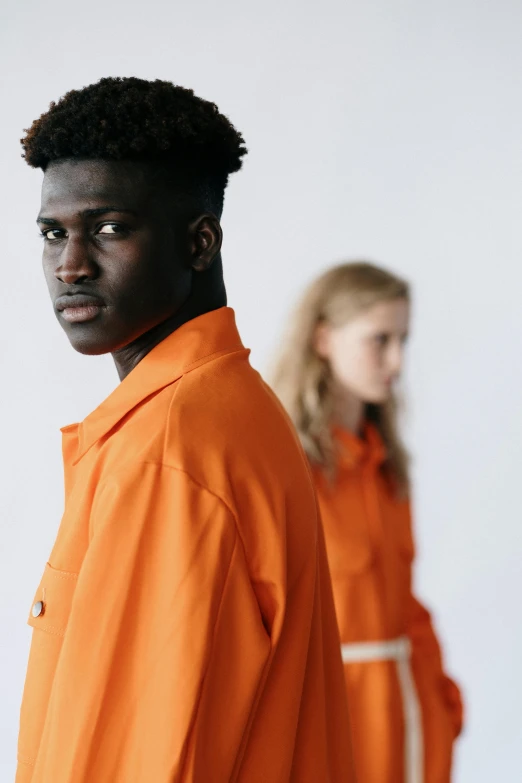 two people in orange outfits with their hair up