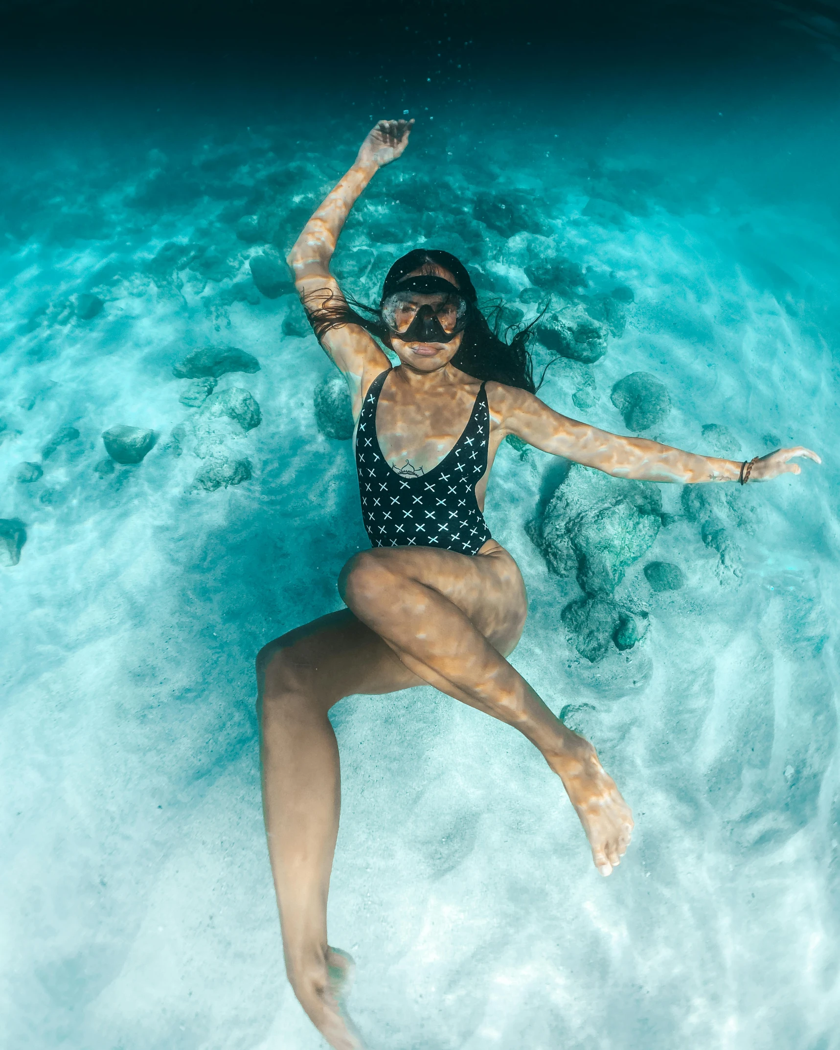 a woman floating in blue water next to shore