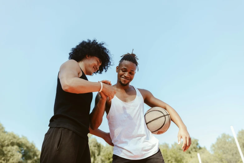 two men with one holding the other's hand while they hold basketballs