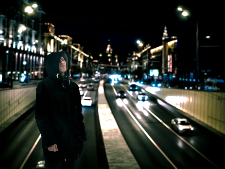 a man in a hooded jacket is looking into the distance while standing on the road