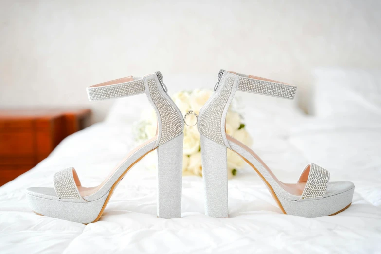 a pair of white high heel shoes with crystal diatrine on them