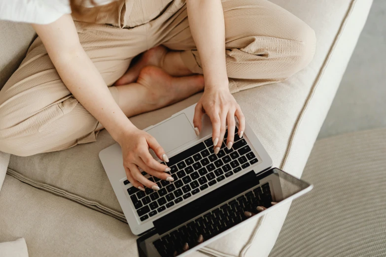 a woman sits on the couch while working on her laptop