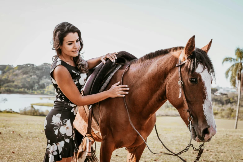 a woman poses with a horse in a large field