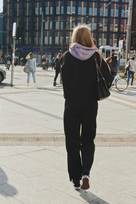a woman walking down the street while wearing all black