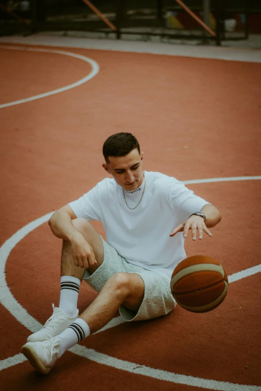 a man holding a basketball sitting on top of a basketball court