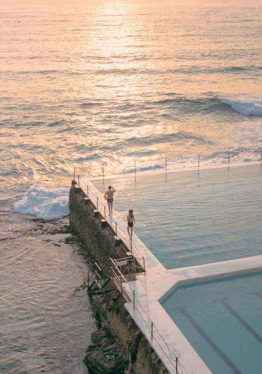 a swimming pool near the ocean has several people walking