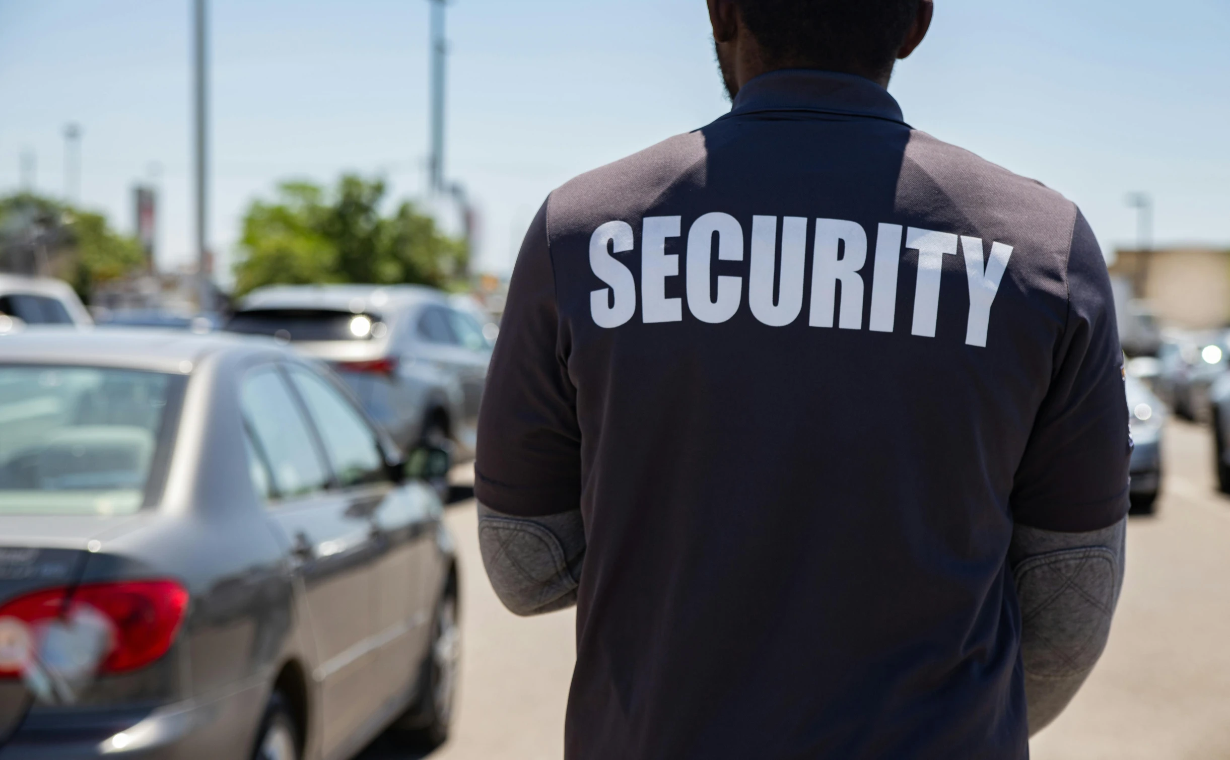 a security officer standing next to several parked cars