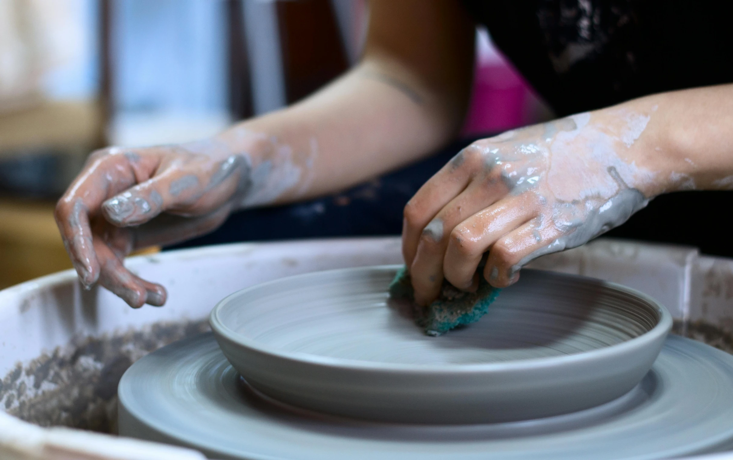 someone working on a pottery wheel with blue paint