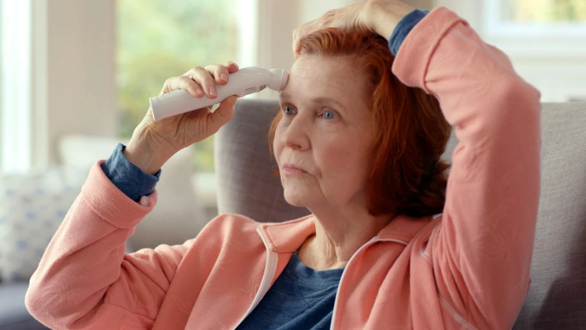 an elderly woman sitting in her chair has a remote control in her hand