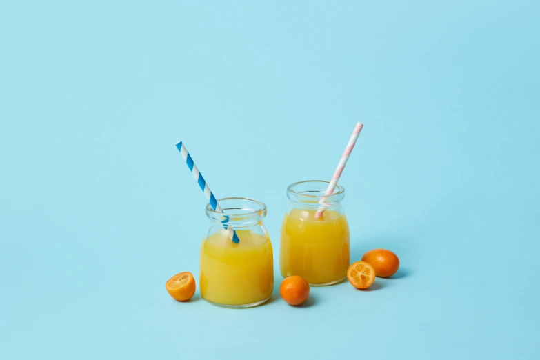 a pair of glasses filled with orange juice on a blue background