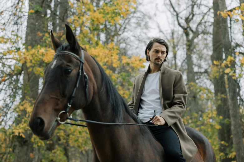 a man with long hair on a horse in the woods