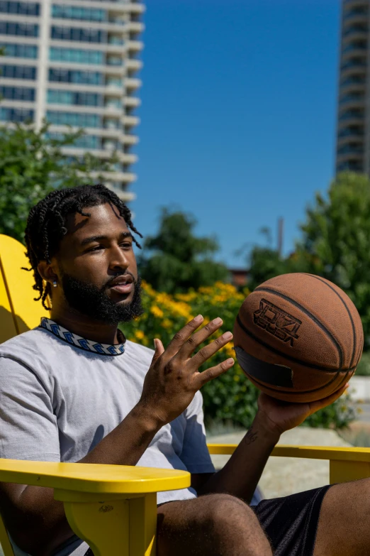 a man sitting on a yellow chair with a basketball in his hand