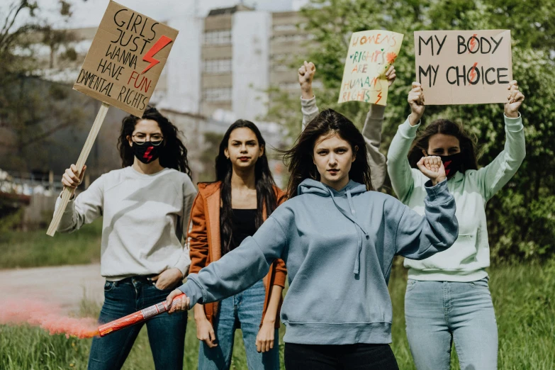 several women hold up signs and stand on grass