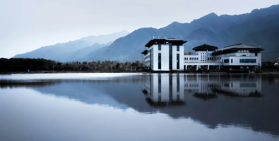 a building in front of mountains with its reflection in the water