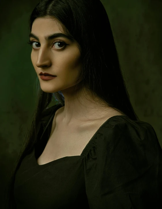 woman with dark hair posing for po next to wall