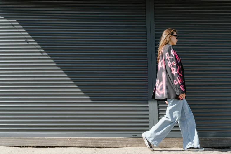 a woman walking on the sidewalk and wearing blue pants