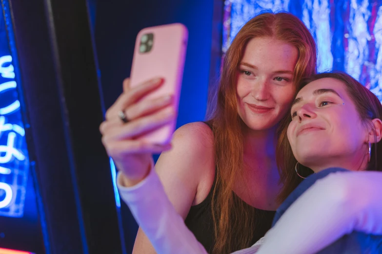 two girls taking pictures with their smartphone