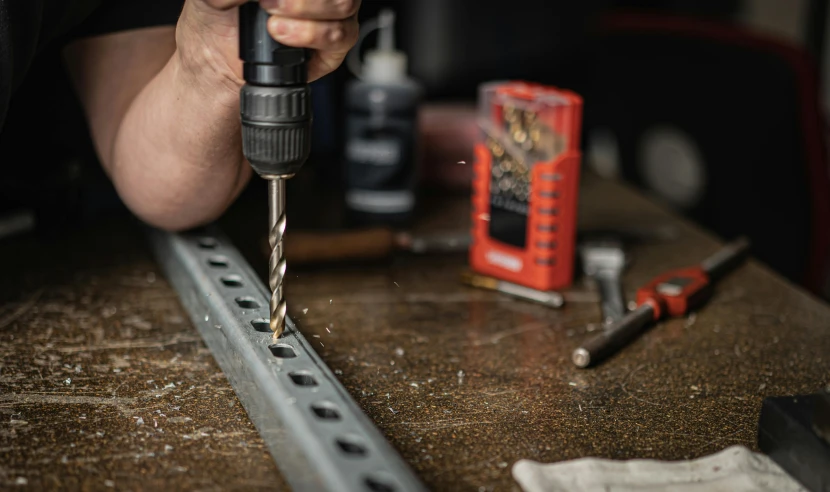 a man making metal part with drill on it