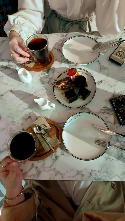 three people sitting at a table with three desserts and cups