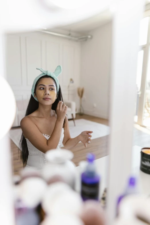 a girl is putting on a towel in front of a mirror