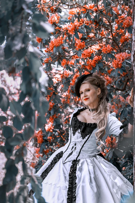 a woman in white and black dress standing near tree