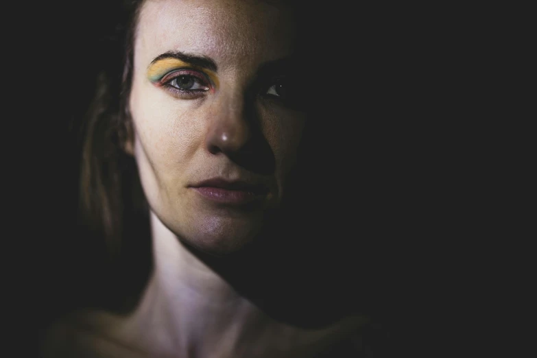 a woman with bright yellow eye makeup in the dark