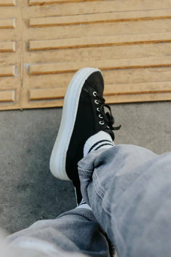 someone in black sneakers with white socks and a plaid sock