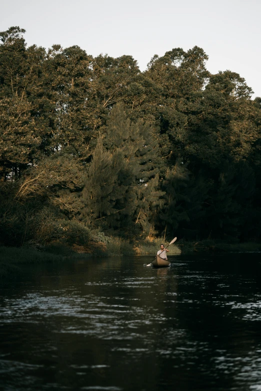 a lone man paddling his canoe out on the river