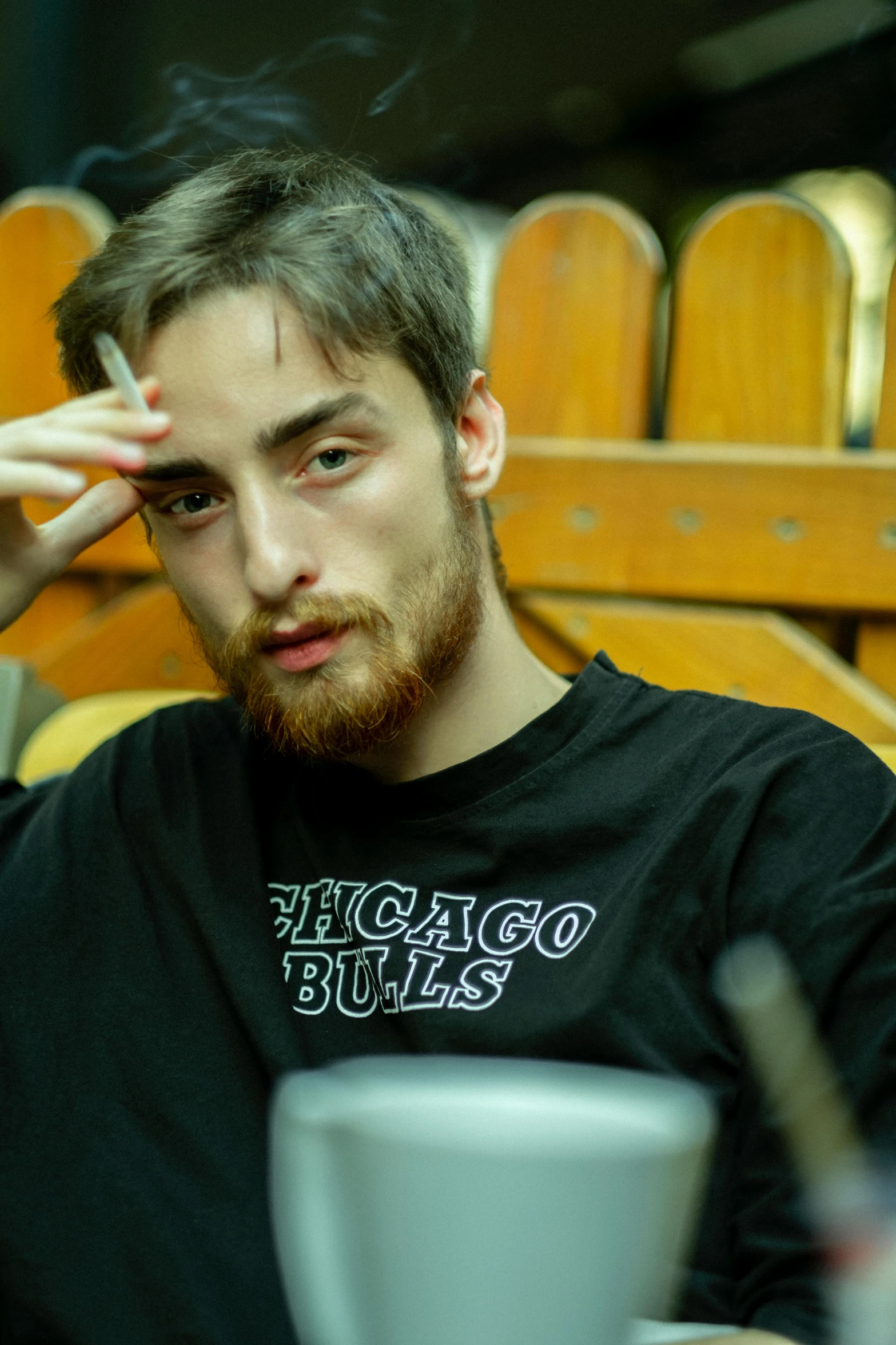 a man that is smoking a cigarette near a cup