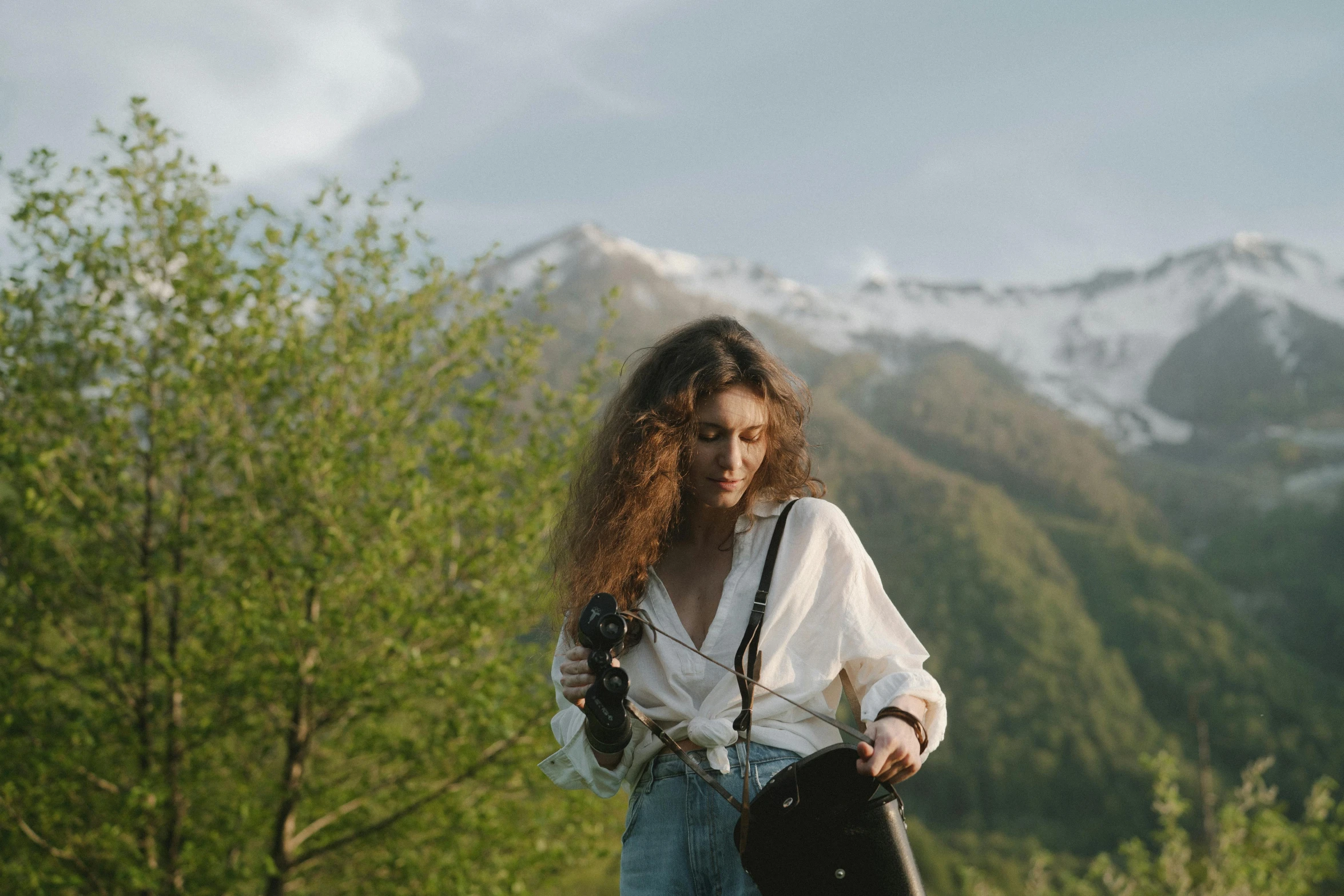 a young woman holding a snowboard while wearing a white shirt and denim overalls