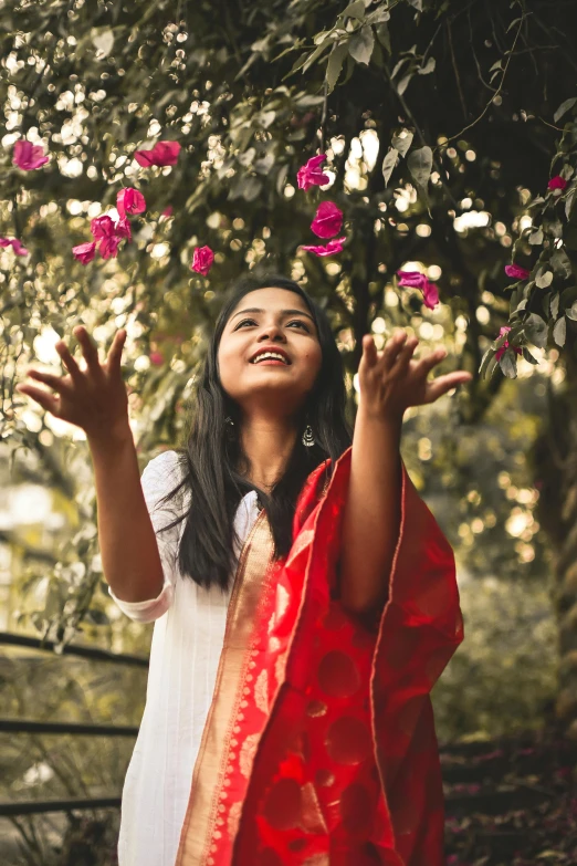 a woman stands in the grass surrounded by pink flowers