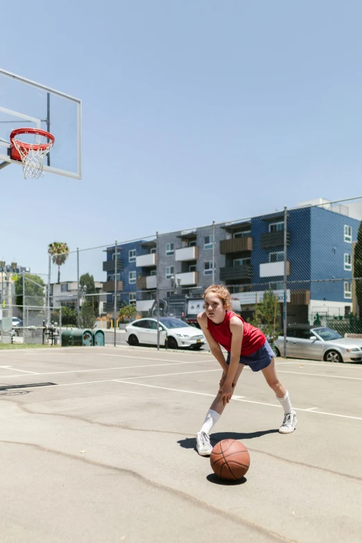 a young woman posing on the basketball court with a basket