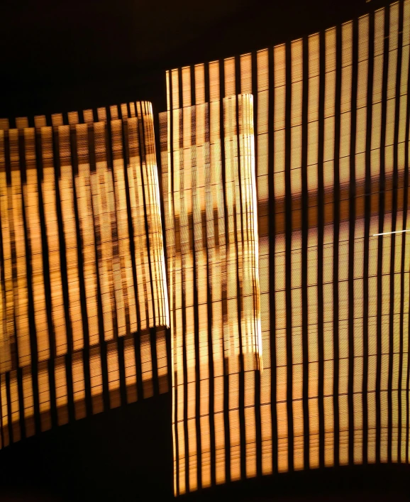 sunlight streams through the bamboo blinds on a wall