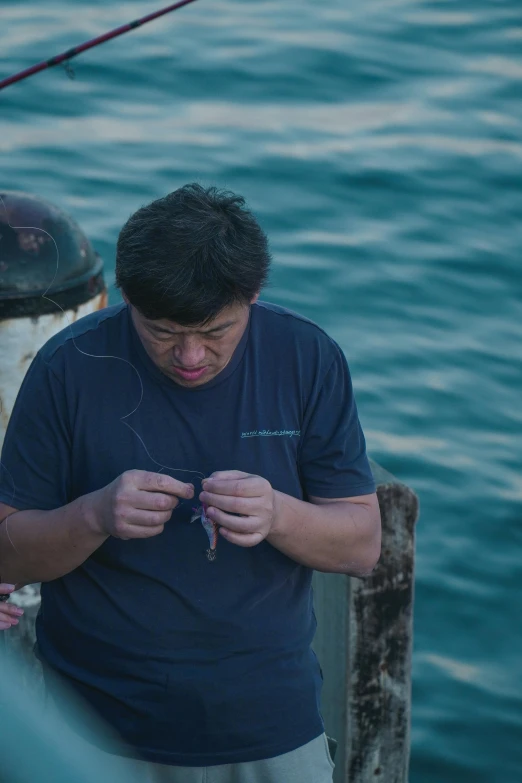 a man on a dock texting while fishing