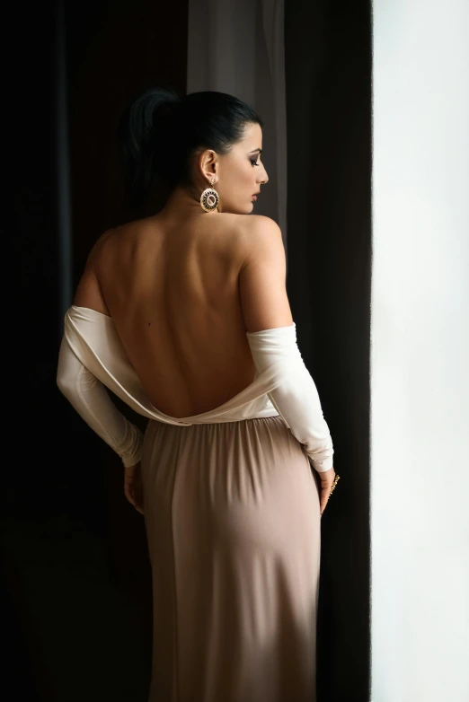 a woman in a white dress leaning against a wall