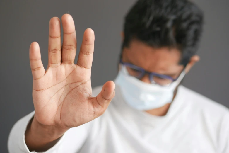 a man wearing a face mask and gesturing while wearing a mouth mask