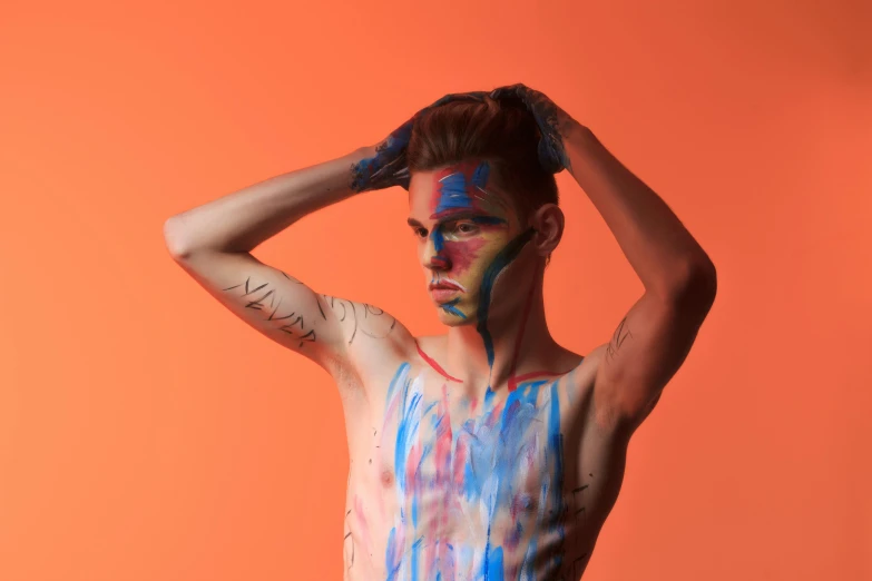 a man wearing paint on his body is standing with his hands behind his head