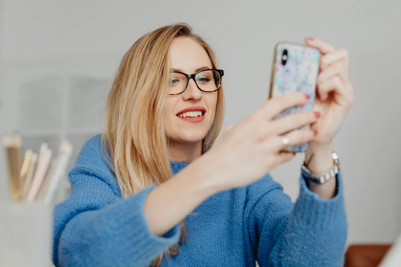 a woman in glasses holding up a cell phone