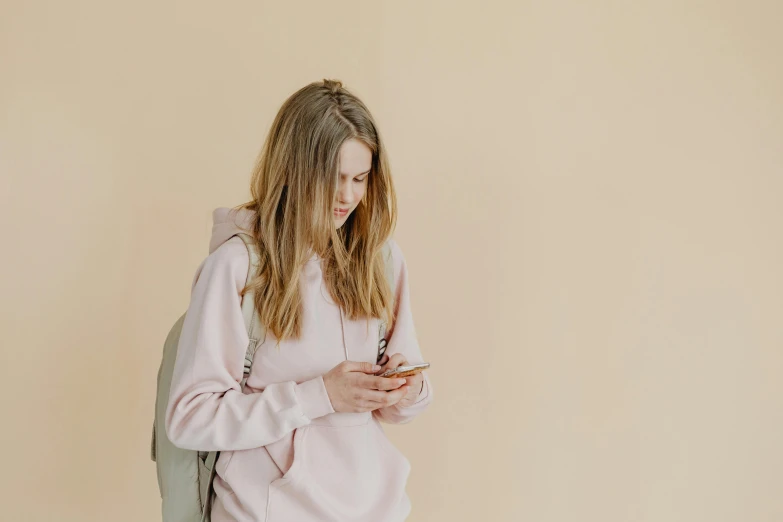 a girl is holding a phone while looking at her backpack