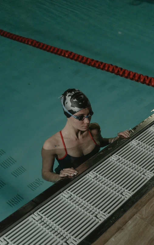 a woman in sunglasses and an inflatable swimming suit is leaning up against a tiled wall