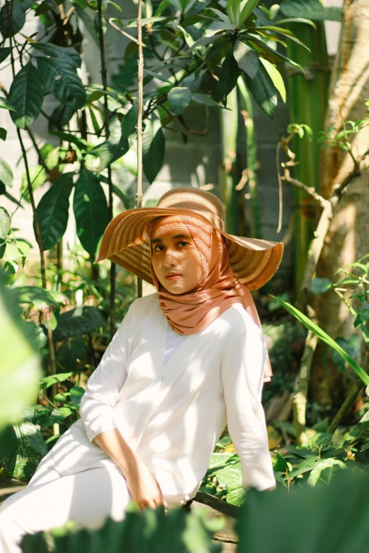 a woman sits in the woods with a paper hat