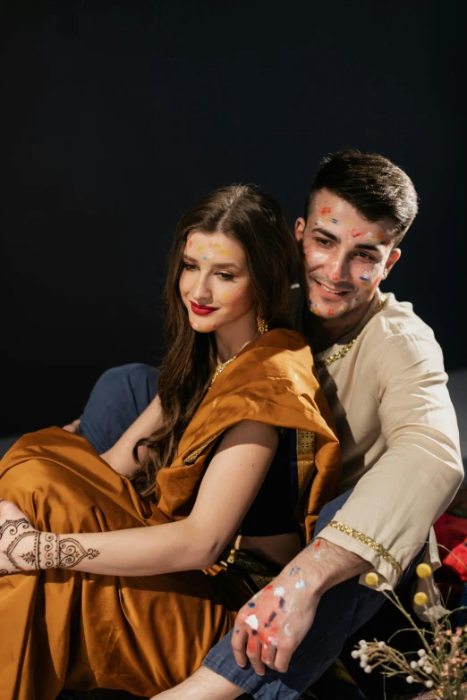 a couple is sitting on the couch while dressed up in indian garb