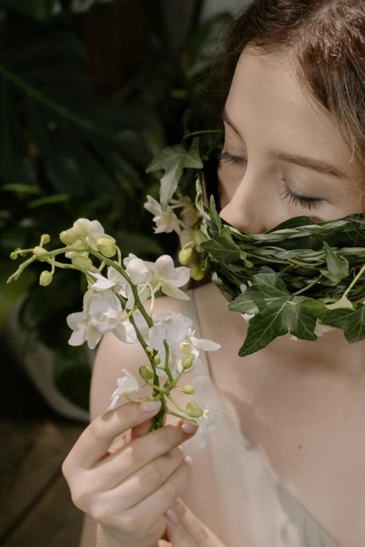 woman holding a bouquet of flowers and leaves as her face covers her eyes