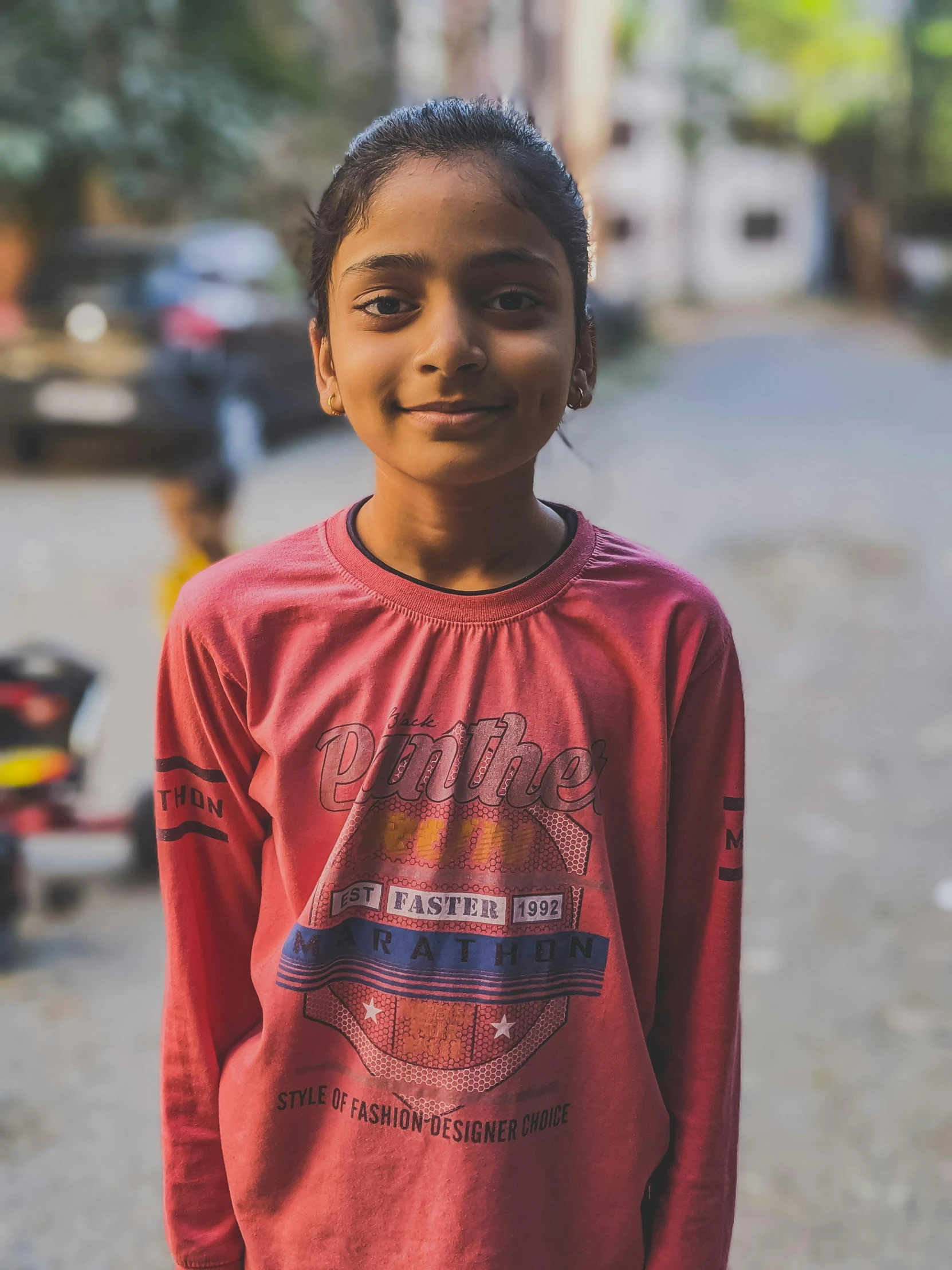 a little girl smiles as she stands in the middle of the street