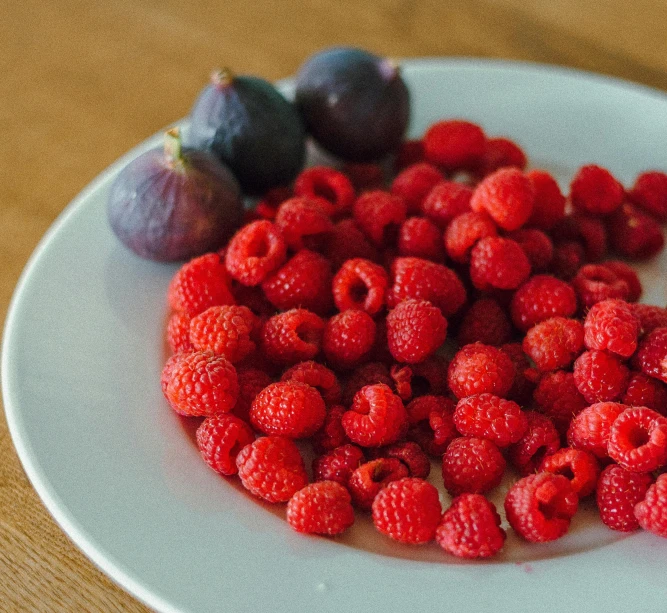 raspberries and berries on a plate sitting on the table